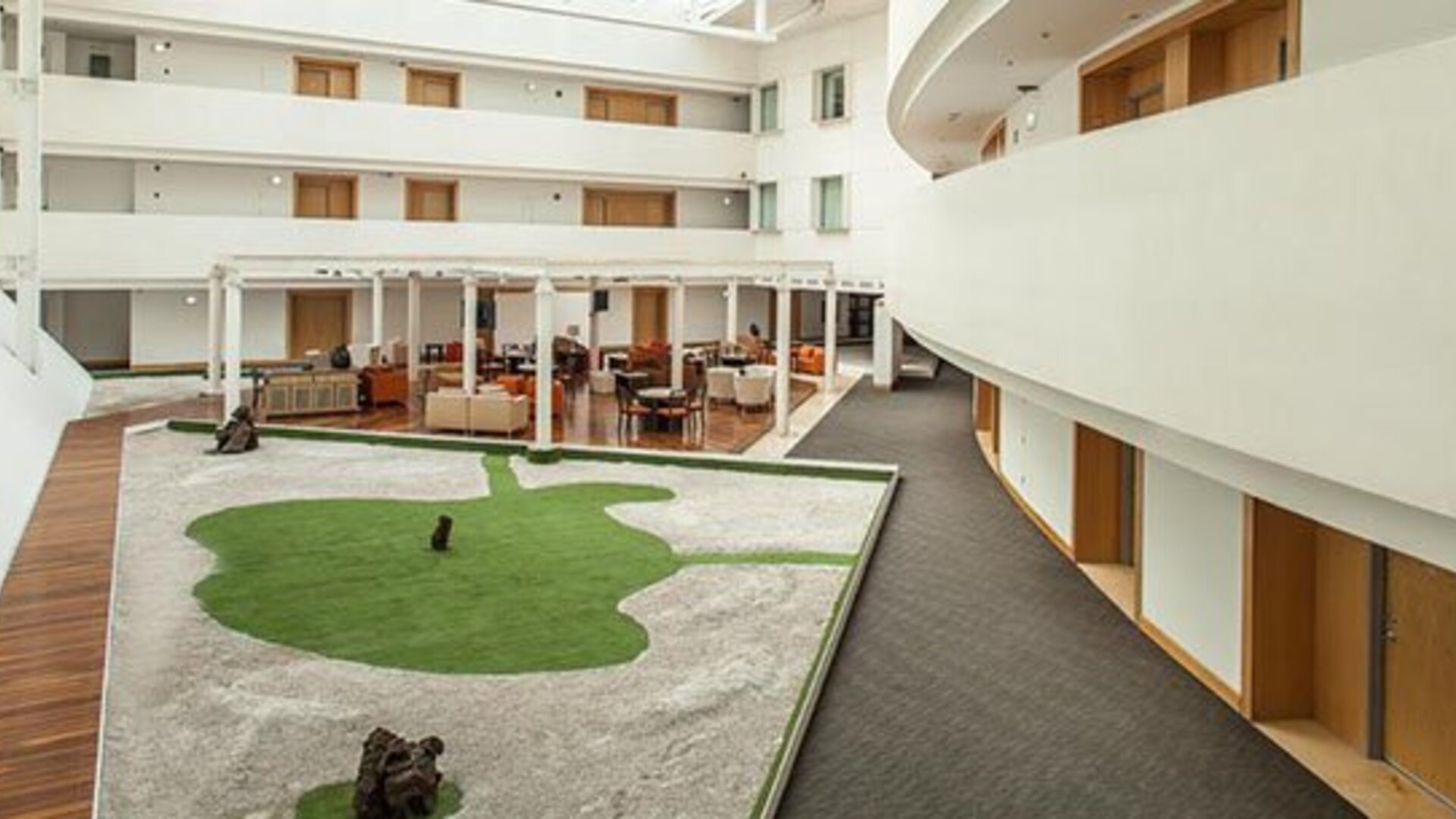 Bright interior courtyard with open atrium, landscaped central garden and comfortable lounge seating at NH Collection Mexico City Airport T2.