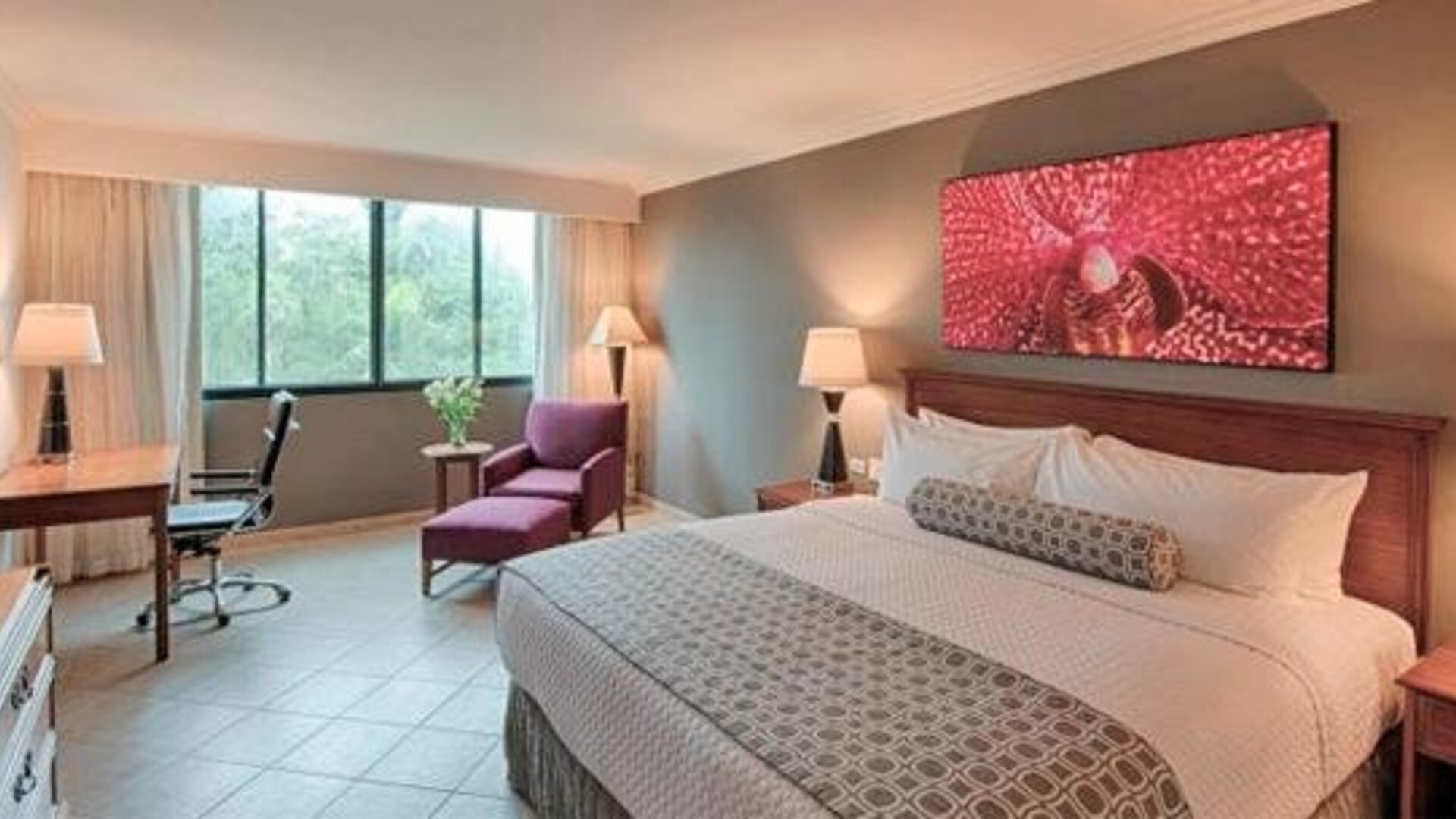 Spacious guest room with king bed, work desk, lounge chair and modern décor at Crowne Plaza Panama.