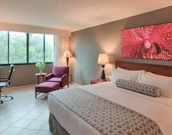 Spacious guest room with king bed, work desk, lounge chair and modern décor at Crowne Plaza Panama.