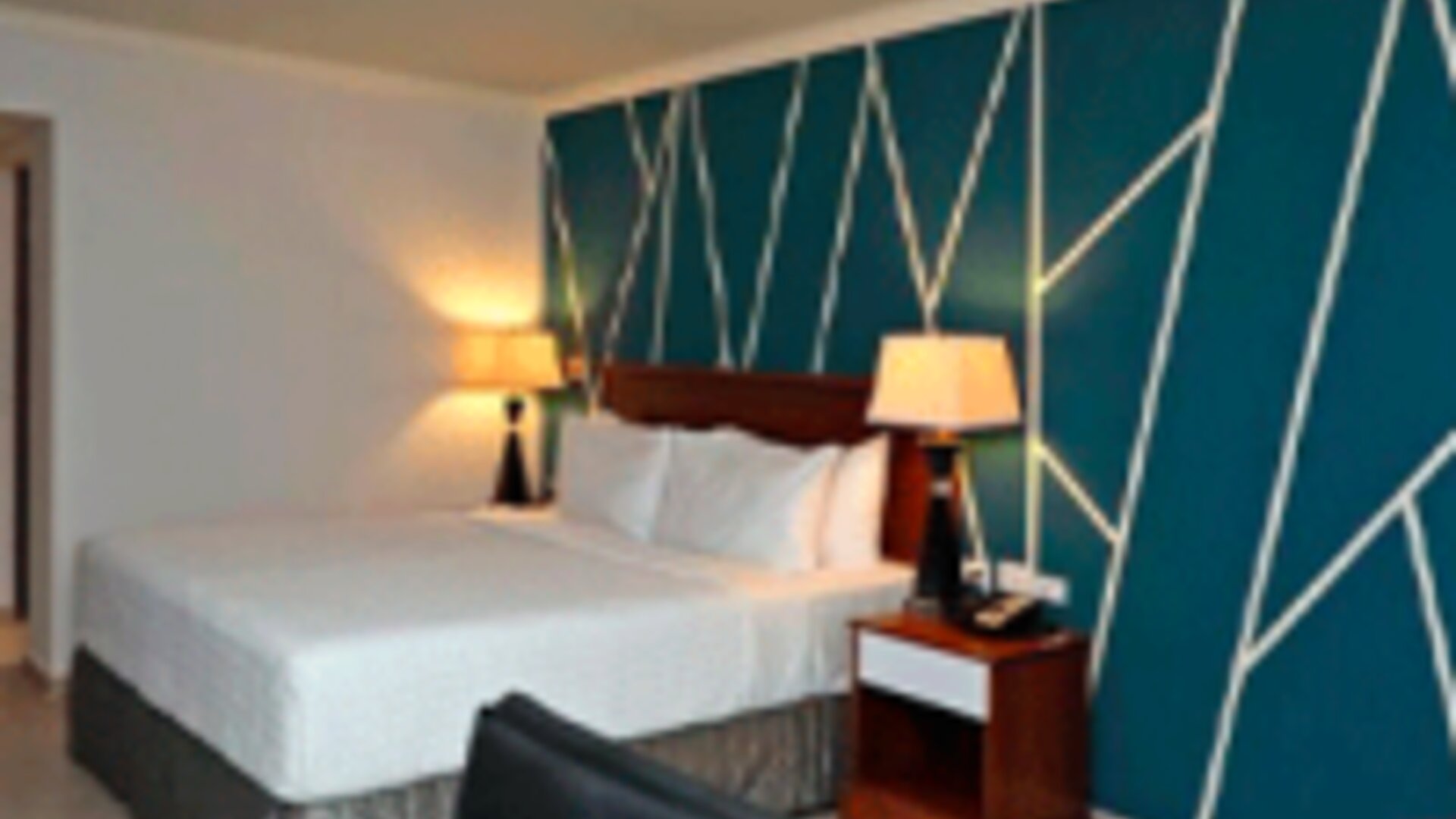 Spacious guest room with king bed, work desk, lounge chair and stylish feature wall at Crowne Plaza Panama.
