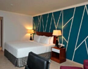 Spacious guest room with king bed, work desk, lounge chair and stylish feature wall at Crowne Plaza Panama.