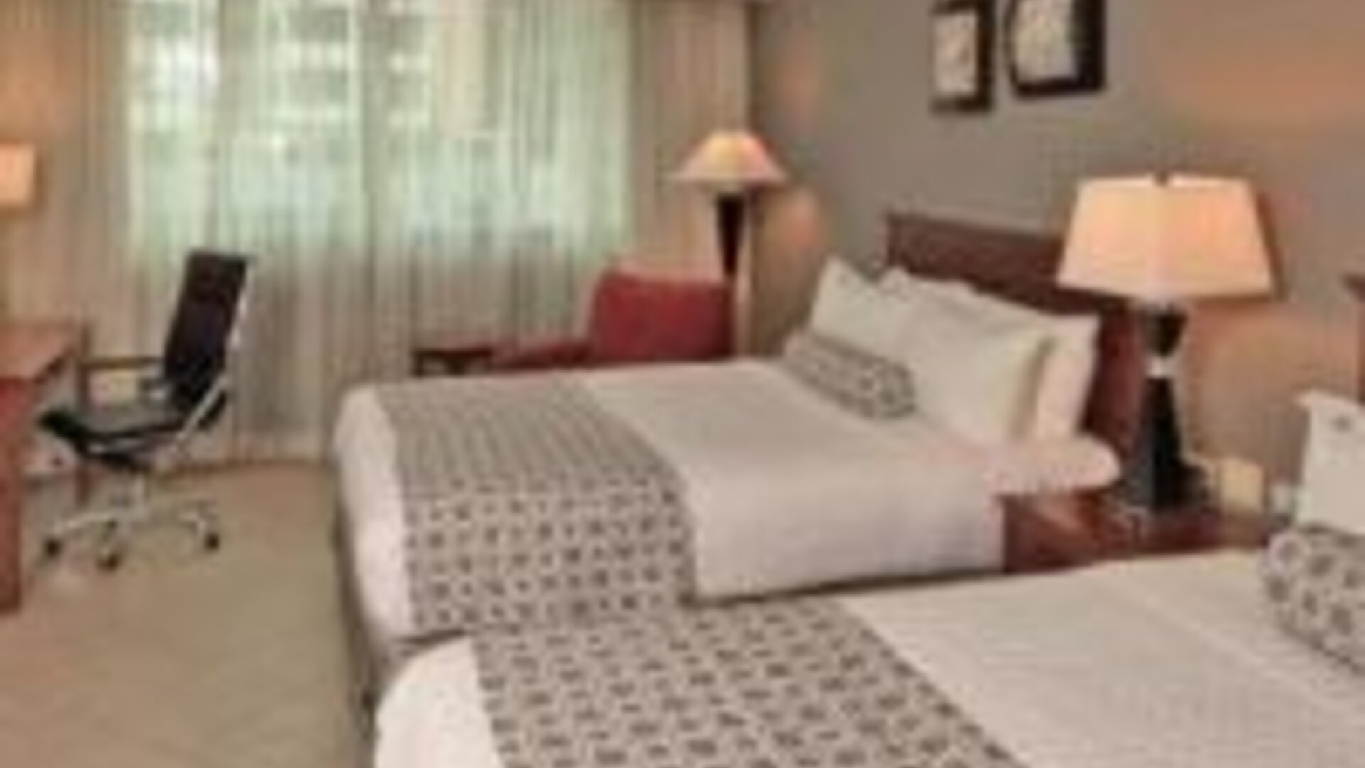 Spacious guest room with two double beds, work desk, lounge chair and large window at Crowne Plaza Panama.