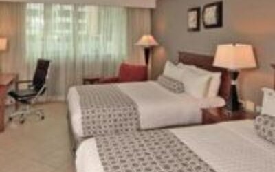 Spacious guest room with two double beds, work desk, lounge chair and large window at Crowne Plaza Panama.