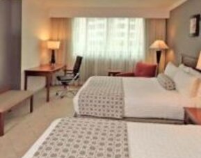 Contemporary guest room featuring two double beds, work area and modern furnishings at Crowne Plaza Panama.
