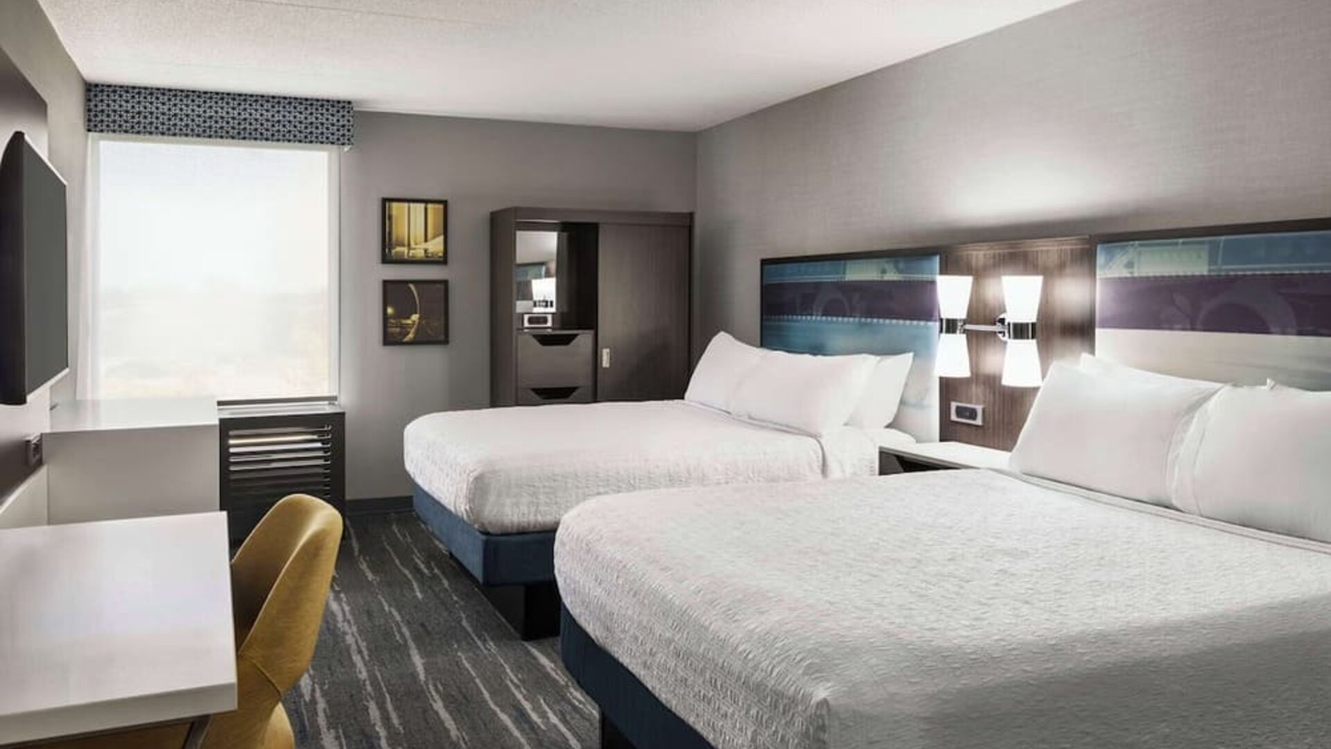 Guest room with two queen beds, work desk, wardrobe and modern amenities at Hampton Inn Chicago O'Hare.