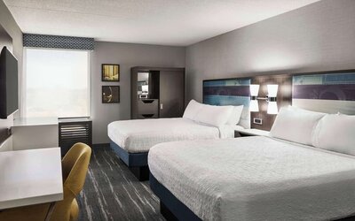 Guest room with two queen beds, work desk, wardrobe and modern amenities at Hampton Inn Chicago O'Hare.
