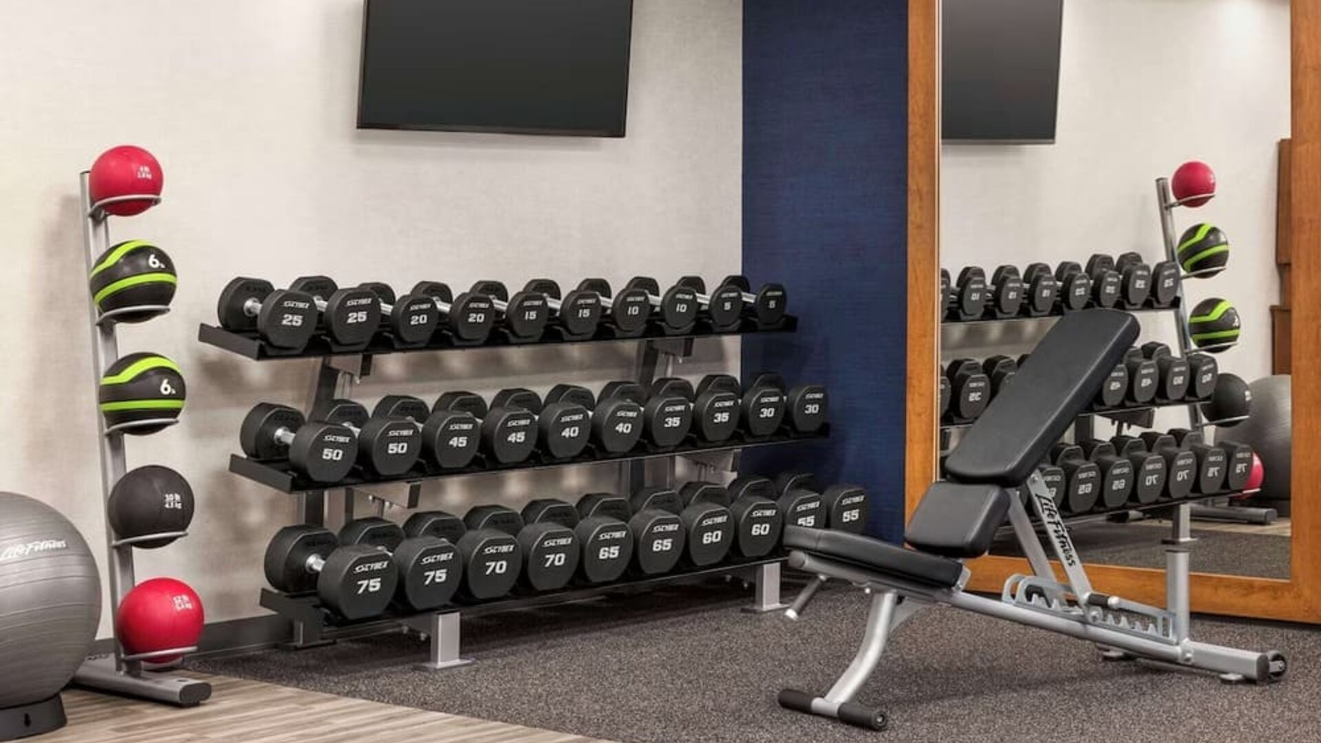 Modern fitness center featuring free weights, adjustable bench, medicine balls and strength training equipment at Hampton Inn Chicago O'Hare.