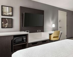 Guest room workspace featuring a flat-screen TV, microwave, mini fridge, desk and ergonomic chair at Hampton Inn Chicago O'Hare.