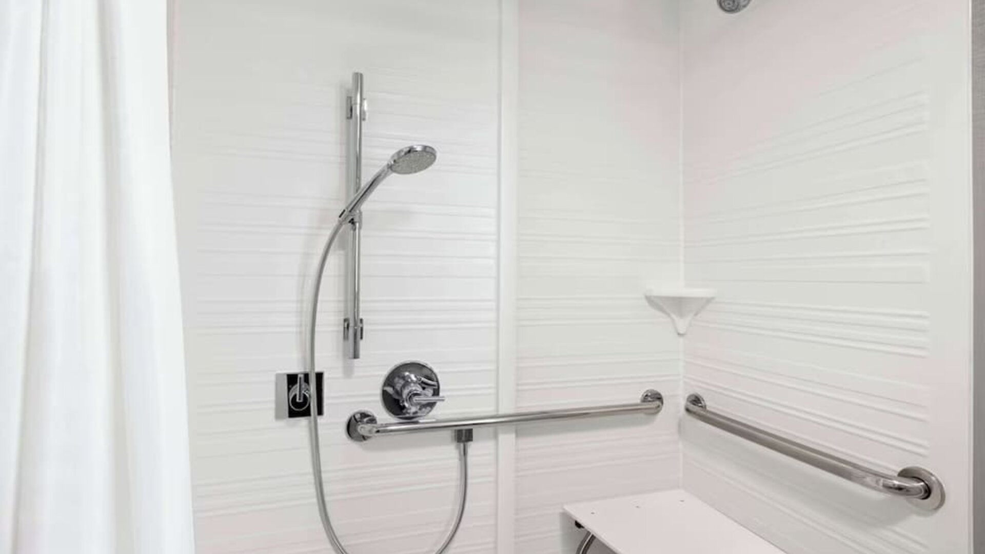 Accessible roll-in shower featuring grab bars, built-in shower seat and accessible bathroom amenities at Hampton Inn Chicago O'Hare.