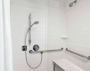 Accessible roll-in shower featuring grab bars, built-in shower seat and accessible bathroom amenities at Hampton Inn Chicago O'Hare.