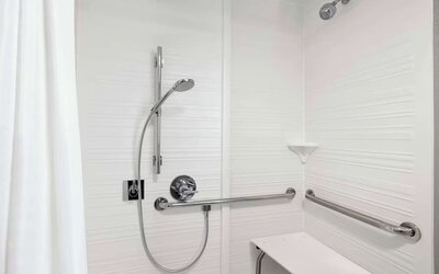Accessible roll-in shower featuring grab bars, built-in shower seat and accessible bathroom amenities at Hampton Inn Chicago O'Hare.