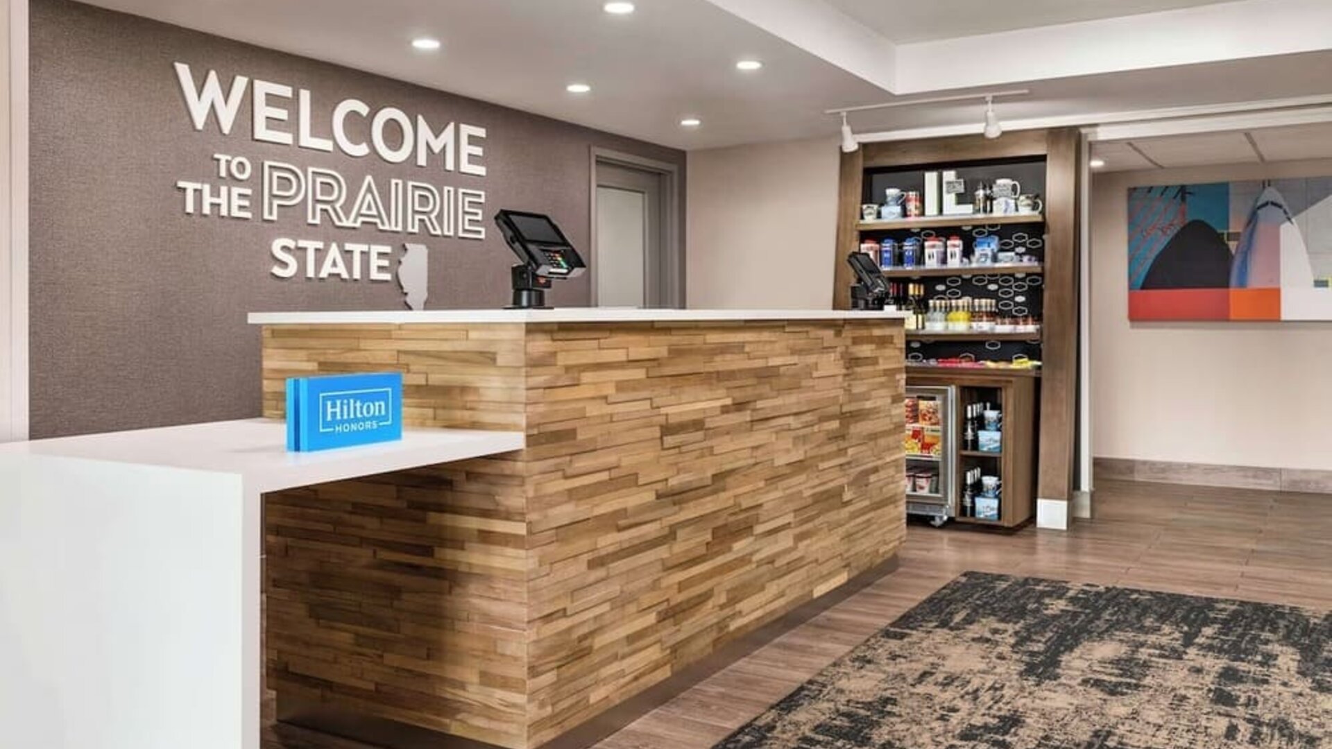 Hotel reception area with front desk, grab-and-go market and welcoming lobby at Hampton Inn Chicago O'Hare.