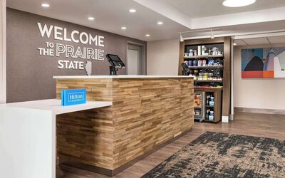 Hotel reception area with front desk, grab-and-go market and welcoming lobby at Hampton Inn Chicago O'Hare.