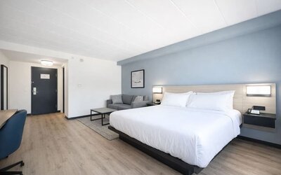 Spacious king guest room featuring a plush bed, sofa, work desk and modern furnishings at Hyatt Select Philadelphia Airport.