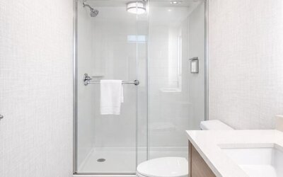 Contemporary guest bathroom with a walk-in glass shower, modern vanity, illuminated mirror and fresh towels at Hyatt Select Philadelphia Airport.