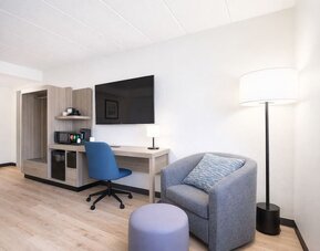 Modern guest room workspace featuring a spacious desk, ergonomic chair, flat-screen TV, mini fridge and coffee station at Hyatt Select Philadelphia Airport.