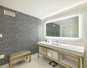 Spacious guest bathroom featuring a double vanity, illuminated mirror and modern walk-in shower at Royal Sonesta Minneapolis.
