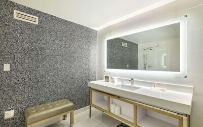 Spacious guest bathroom featuring a double vanity, illuminated mirror and modern walk-in shower at Royal Sonesta Minneapolis.