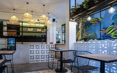 Stylish dining area at 103 Wonderful House featuring colorful tropical wall art, pendant lighting and café-style seating.