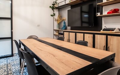 Meeting and seating area at 103 Wonderful House featuring a large wooden table, chairs, flat-screen TV and modern shelving.