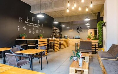 Café-style dining area at Hotel Loft 32 featuring wooden tables, lounge seating, greenery and modern lighting.