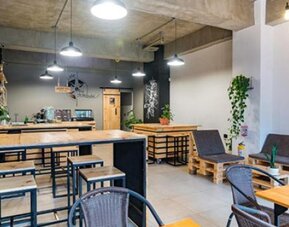 Dining and lounge area at Hotel Loft 32 featuring wooden tables, casual seating, pendant lights and contemporary industrial décor.