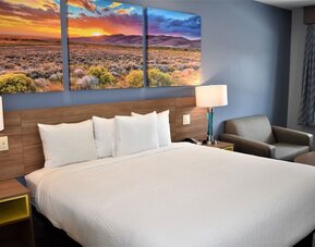 King guest room at Days Inn & Suites By Wyndham Downtown/University Of Houston featuring a king bed, bedside lamps and a seating area.