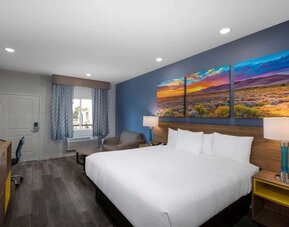 Spacious king room at Days Inn & Suites By Wyndham Downtown/University Of Houston featuring a king bed, seating area, work desk and flat-screen TV.