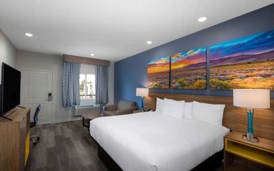 Spacious king room at Days Inn & Suites By Wyndham Downtown/University Of Houston featuring a king bed, seating area, work desk and flat-screen TV.