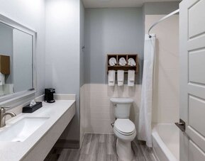 Guest bathroom at Days Inn & Suites By Wyndham Downtown/University Of Houston featuring a vanity, toilet and shower-tub combination.