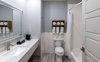 Guest bathroom at Days Inn & Suites By Wyndham Downtown/University Of Houston featuring a vanity, toilet and shower-tub combination.