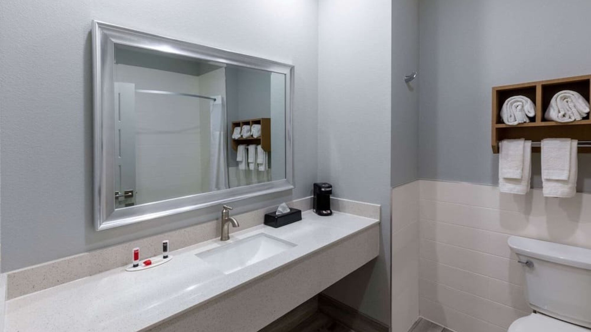 Modern bathroom at Days Inn & Suites By Wyndham Downtown/University Of Houston featuring a spacious vanity, large mirror and fresh towels.