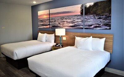 Guest room at Days Inn & Suites By Wyndham Downtown/University Of Houston featuring two beds and colorful scenic wall artwork.