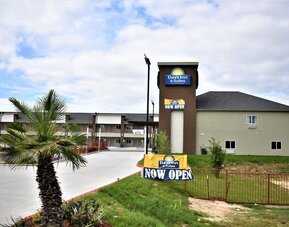 Exterior view of Days Inn & Suites By Wyndham Downtown/University Of Houston featuring the hotel building and prominent roadside signage.