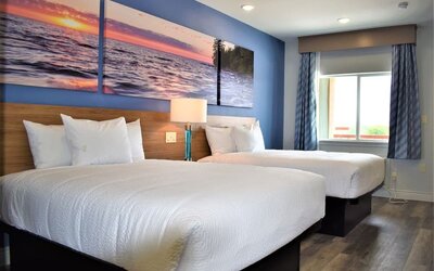 Guest room at Days Inn & Suites By Wyndham Downtown/University Of Houston featuring two beds, a large window and natural light.