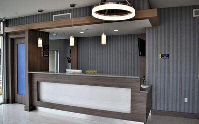 Reception desk at Days Inn & Suites By Wyndham Downtown/University Of Houston featuring contemporary wood finishes and pendant lighting.