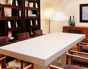 Meeting room at Hotel Pulitzer Buenos Aires featuring a large central table, upholstered chairs, bookshelves and contemporary lighting.