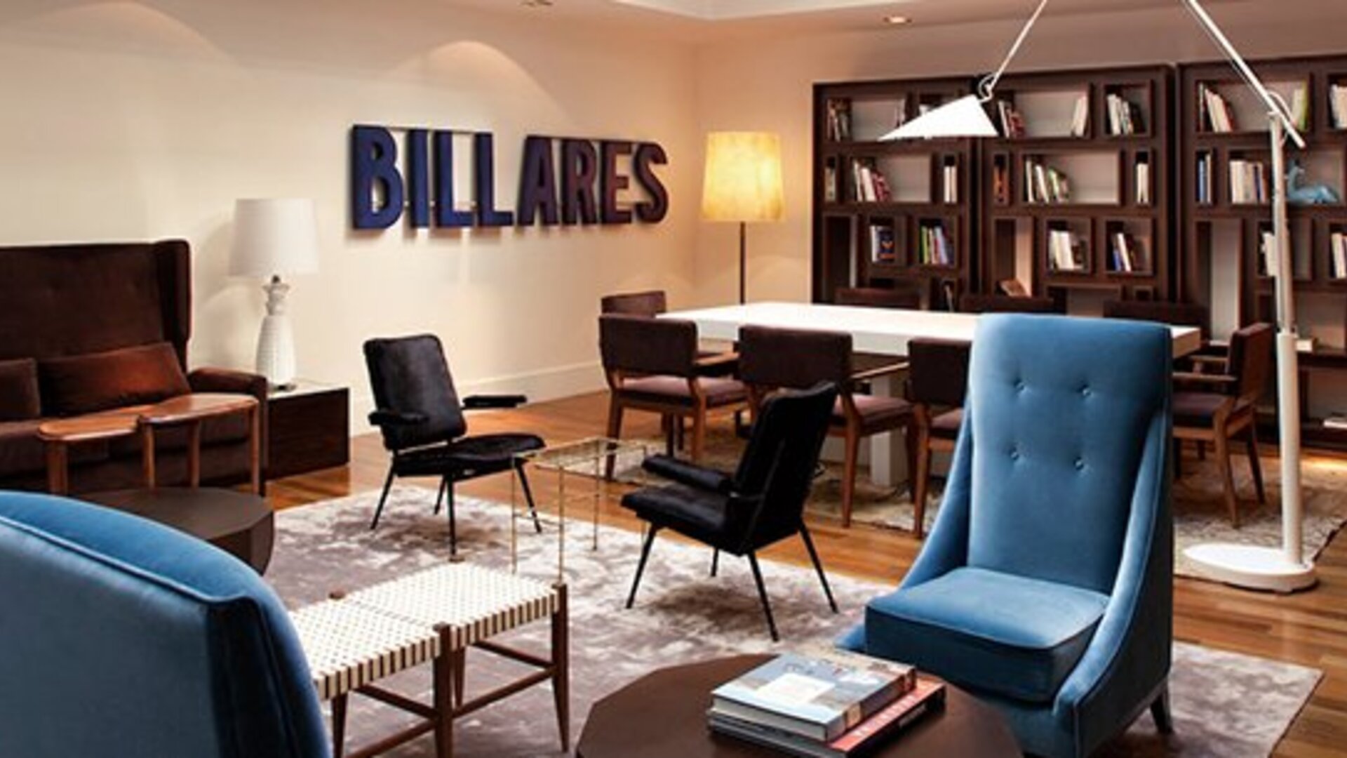 Lounge and meeting area at Hotel Pulitzer Buenos Aires featuring comfortable seating, bookshelves and a communal table.