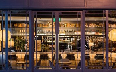 Hotel bar at Hotel Pulitzer Buenos Aires featuring a well-stocked bar, counter seating and warm ambient lighting.