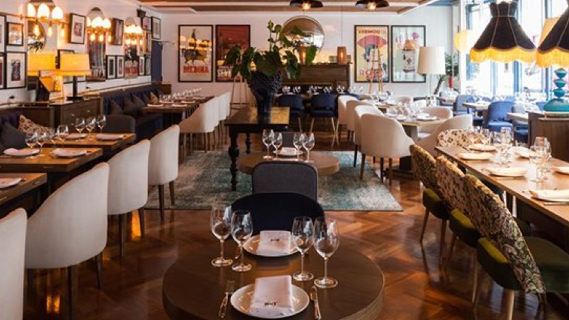 Restaurant at Hotel Pulitzer Buenos Aires featuring elegant table settings, stylish seating and eclectic wall décor.