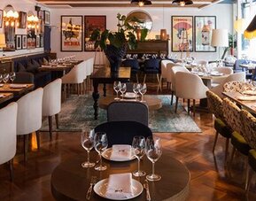 Restaurant at Hotel Pulitzer Buenos Aires featuring elegant table settings, stylish seating and eclectic wall décor.