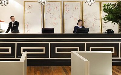 Reception desk at Hotel Pulitzer Buenos Aires featuring a sophisticated black-and-white counter, decorative wall panels and hotel staff.