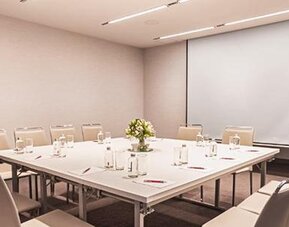 Meeting room at NH Collection Mexico City Centro Histórico featuring a conference table, chairs and projection screen.