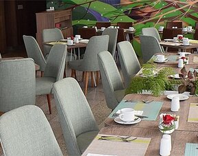 Restaurant at Holiday Inn Lima Airport featuring neatly arranged dining tables, upholstered chairs and colorful wall artwork.