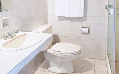 Guest bathroom at Hotel Benidorm featuring a sink, toilet and glass-enclosed shower.