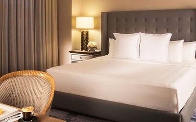 Spacious guest room at Hotel Marquis Reforma featuring a king bed, bedside lamps and a dining area.