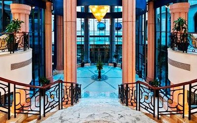 Grand interior staircase at Hotel Marquis Reforma featuring curved railings, marble finishes and a glass atrium.