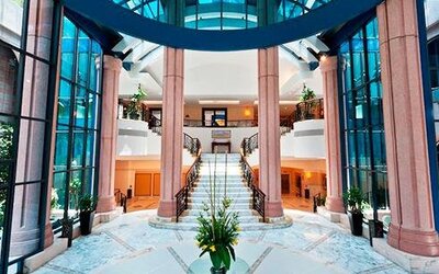 Elegant lobby at Hotel Marquis Reforma featuring blue tufted sofas, large round mirrors and modern seating.