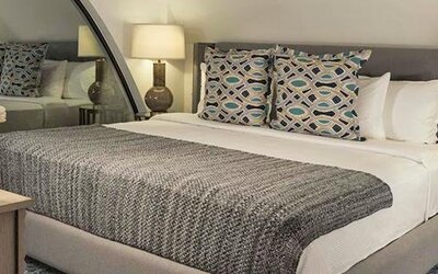 Guest room at Hotel Marquis Reforma featuring a king bed, patterned cushions, bedside lamps and contemporary furnishings.
