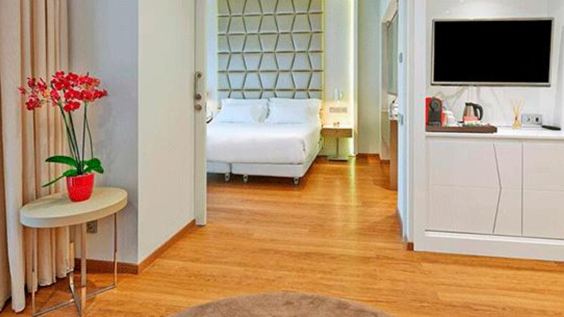 Spacious suite featuring wood flooring, a separate sleeping area, television and coffee station at NH Collection Barcelona Pódium.